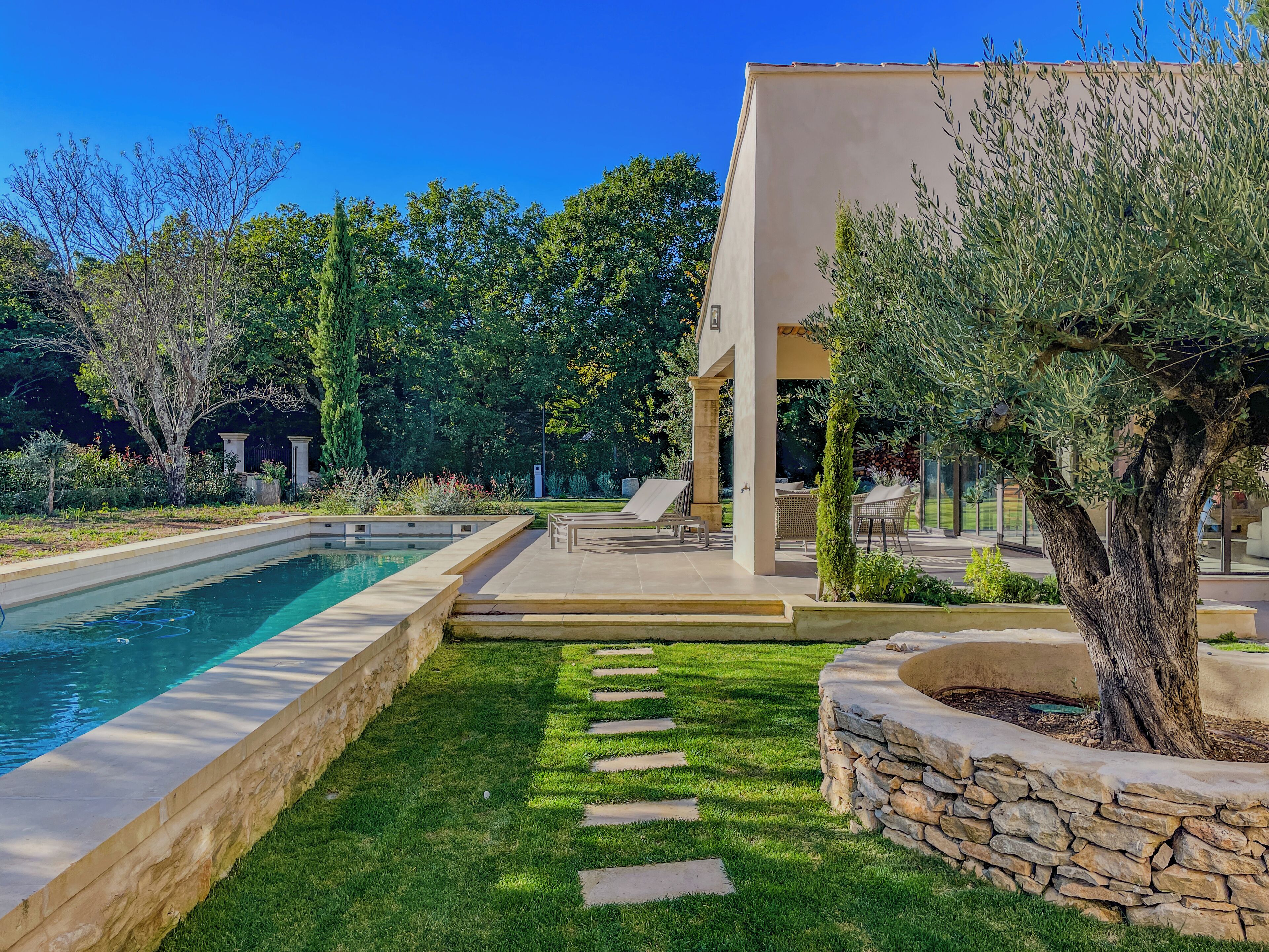 A modern outdoor pool area with a stone-lined pool, a stone pathway, and outdoor seating.