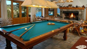 A pool table with a fire pit and a television in the background.