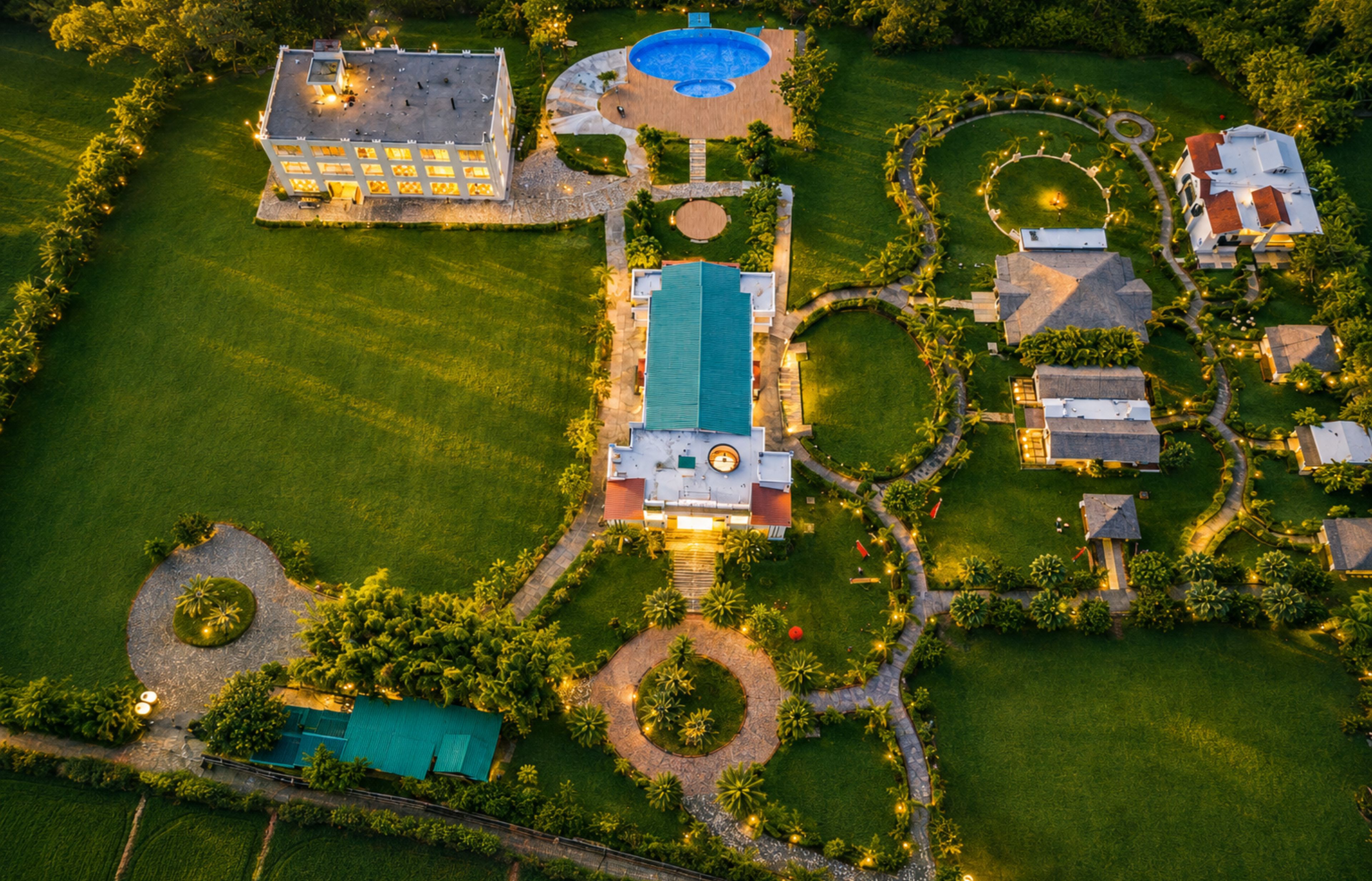 An aerial view of a resort with a swimming pool, multiple buildings, and landscaped gardens.