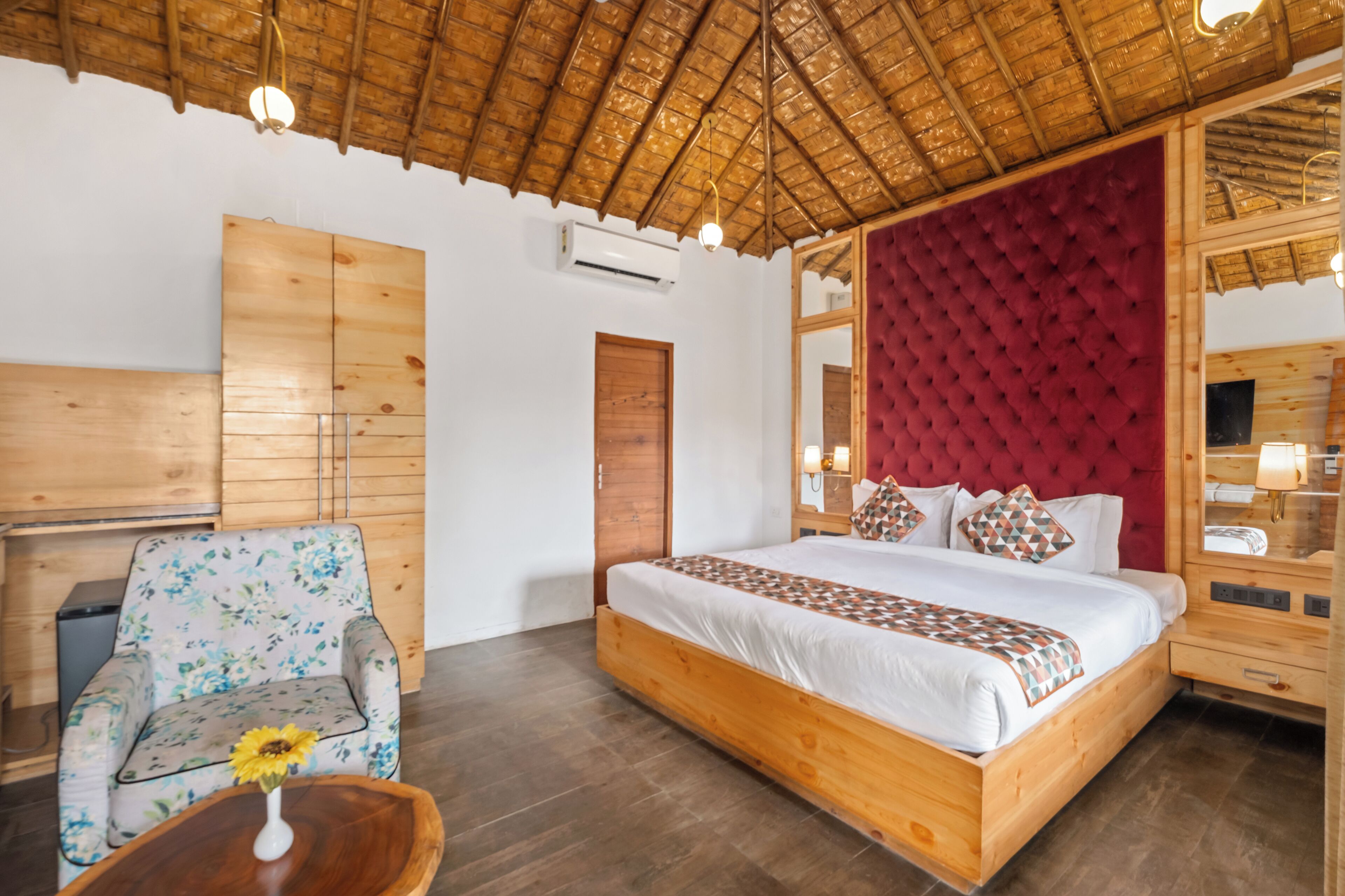 A room with a wooden bed, a floral armchair, a wooden nightstand, and a mirror.