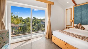 A bedroom with a large sliding glass door leading to a balcony, a bed with a geometric-patterned bedspread, and a blue upholstered headboard. - Corbett Selva Resort By DevStayz -Pet-Friendly Resort (Ramnagar)