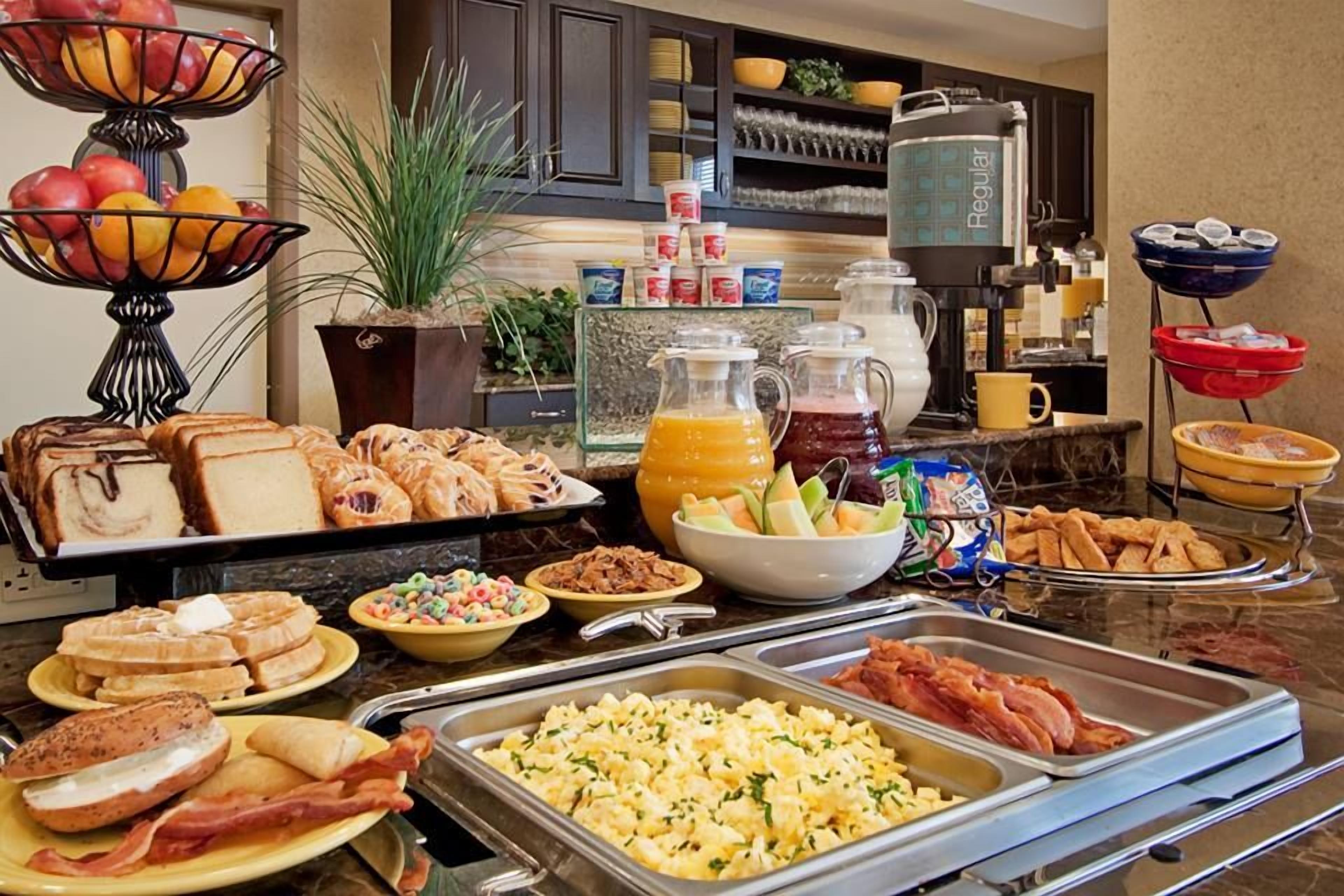 Un bufé con diferentes opciones de desayuno, como pasteles, frutas y bebidas.