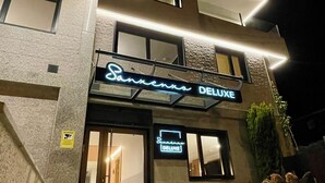 Een hotel genaamd 'Sanxenxo DELUXE' met een moderne gevel, meerdere ramen en een goed verlichte ingang.