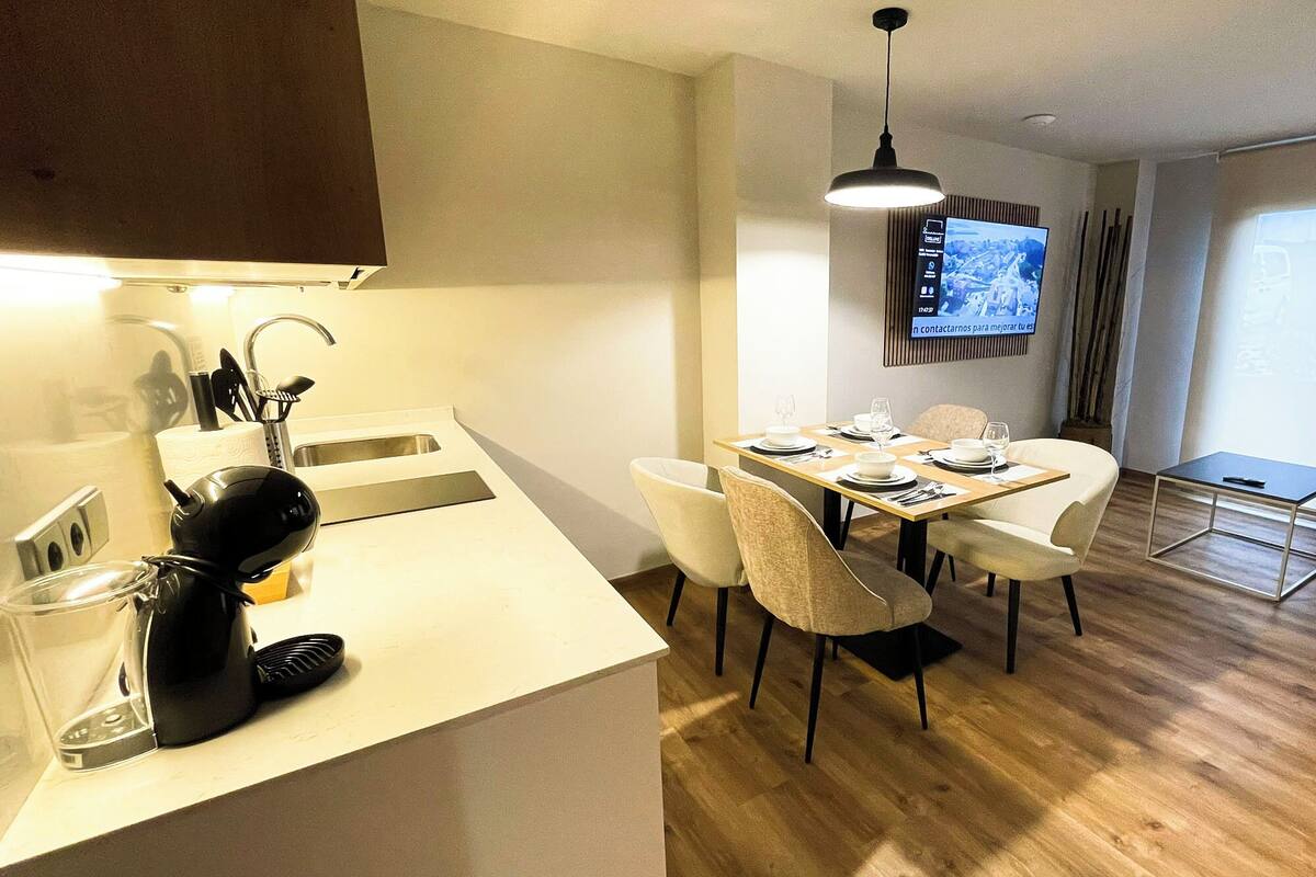 Une cuisine moderne avec un coin repas, un téléviseur fixé au mur et un canapé dans le salon.