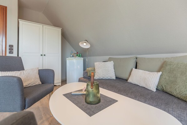 Een moderne woonkamer met een grijze bank, een witte salontafel en een lamp.