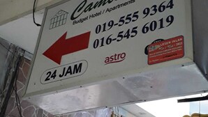 Señal del Cambridge Budget Hotel con números de contacto e indicación de servicio las 24 horas.