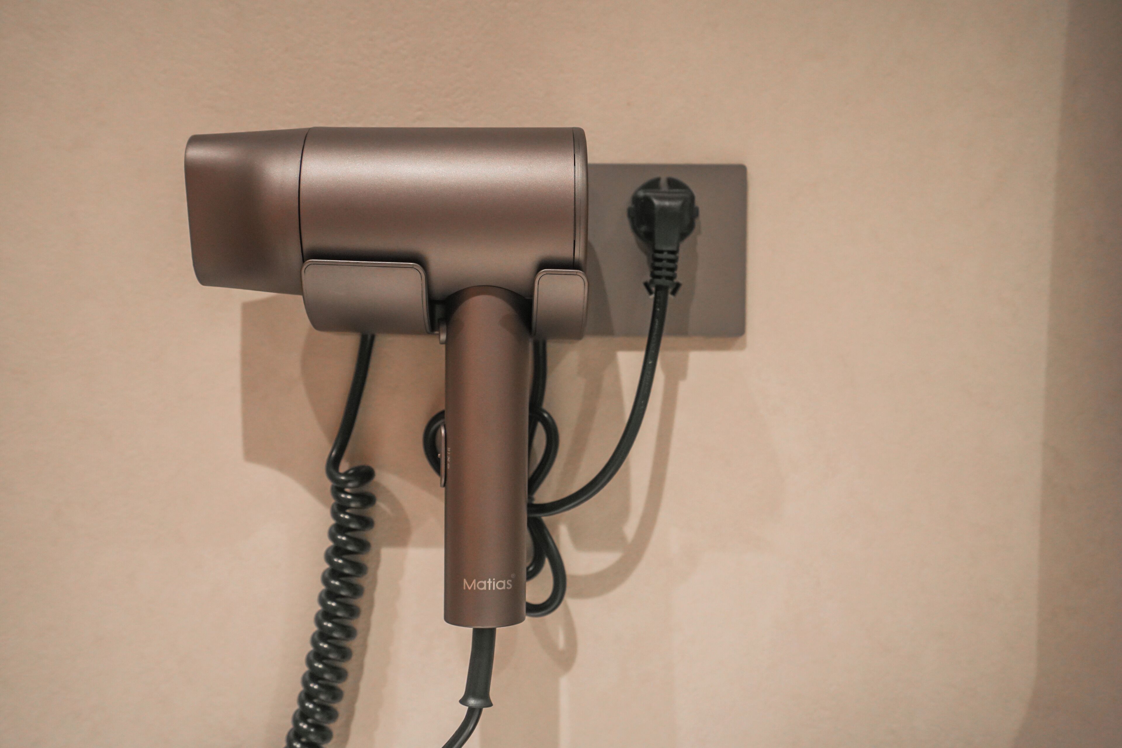 Ein an der Wand befestigter Haartrockner mit Kabel.