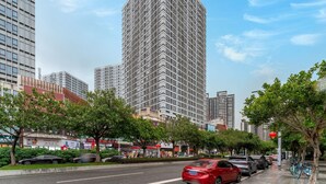 Un rascacielos alto y moderno con fachada de entramado, rodeado de calles urbanas y vegetación.
