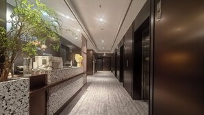Un pasillo moderno de hotel con una recepción, una máquina de café y una planta en maceta.