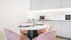 A modern kitchen with a round dining table, two chairs, and a countertop with a coffee machine. - Easylife - Duomo Deluxe Apartments #1 (Milano)