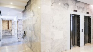 A modern lobby with marble flooring and walls, a staircase, and two elevators. - Easylife - Duomo Deluxe Apartments #1 (Milano)