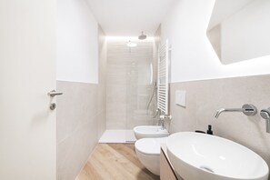Un baño moderno con ducha, dos inodoros y lavamanos.