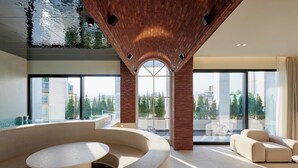 Un interno moderno con una zona salotto dalle linee curve, ampie finestre e un soffitto in mattoni.