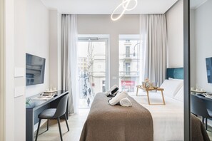 Ein modernes Hotelzimmer mit Bett, Schreibtisch und Fernseher. Blick auf die Straße.