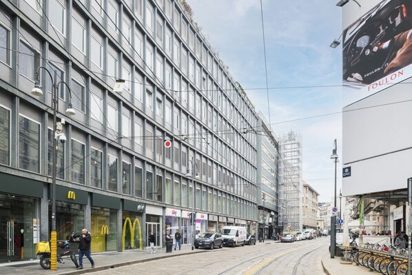 Ein modernes Gebäude mit mehreren Schaufenstern, darunter ein McDonald's und eine Sky Travel Agentur.