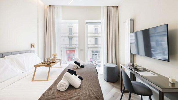 Une chambre d’hôtel avec un lit, un bureau, une télévision et une vue sur la ville.