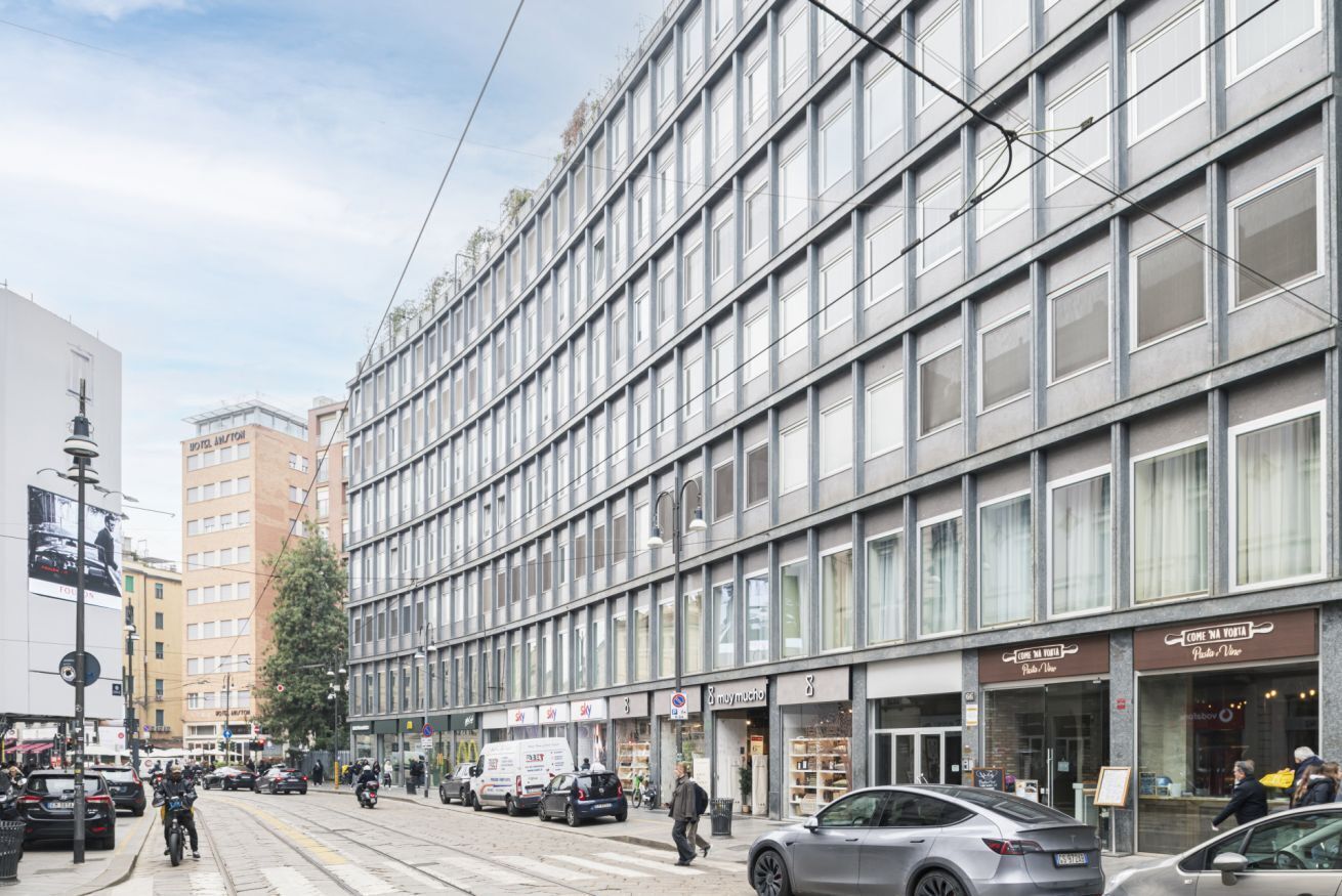 A modern building with multiple storefronts on the ground floor, including a bakery and a furniture store.