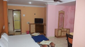 Una habitación de hotel con una cama, televisión, cómoda y espejo.