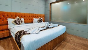 Habitación de hotel con una cama grande, cabecera de madera, un ventanal amplio y un equipo de aire acondicionado.