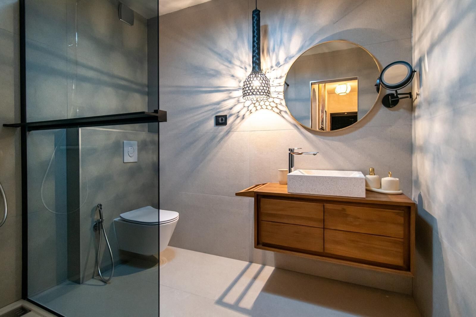 A modern bathroom with a glass shower enclosure, a wooden vanity with a sink, and a large mirror.