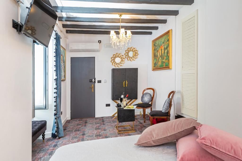 Quarto com cama, escrivaninha, cadeira, lustre e obras de arte nas paredes.