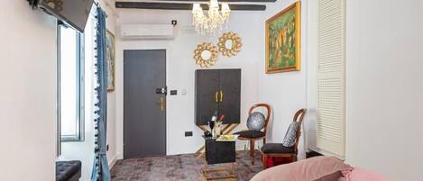 Quarto com cama, escrivaninha, cadeira, lustre e obras de arte nas paredes.