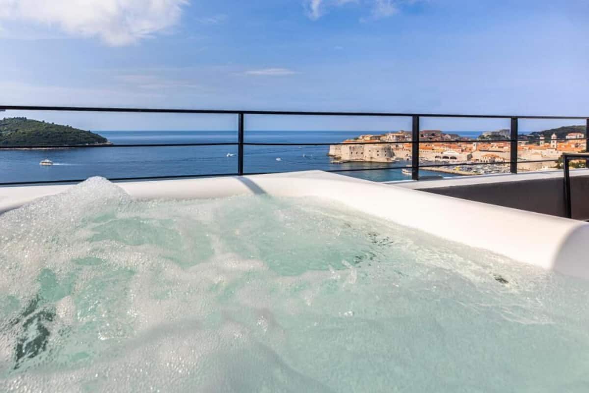 Un jacuzzi con vista despejada a un pueblo costero y una pequeña isla al fondo.