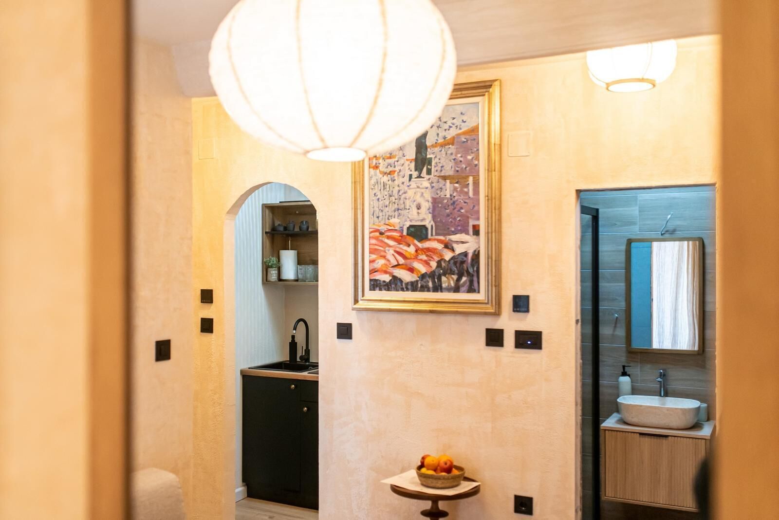 Un baño moderno con lavamanos, espejo y un cuadro sobre el espejo.