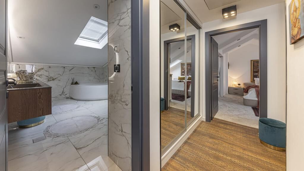 Un baño moderno con pared de mármol, una bañera y un tocador de madera.
