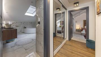 Un baño moderno con pared de mármol, una bañera y un tocador de madera.