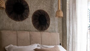 Une chambre avec un grand lit, deux lampes murales en osier et un panier de fruits sur une table de chevet.