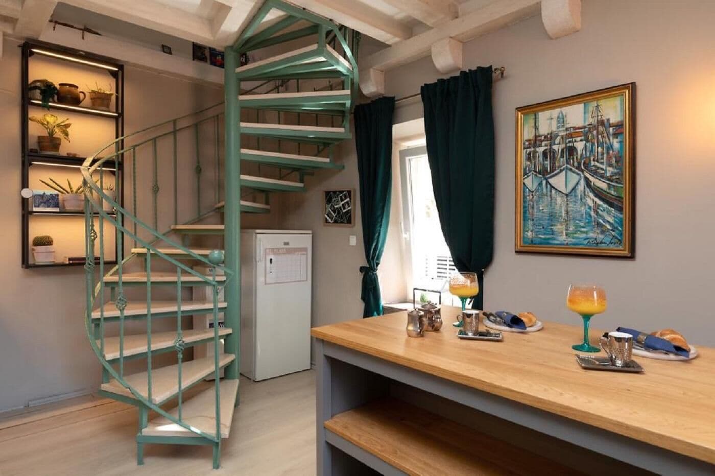 Una cocina compacta con una escalera en espiral, un refrigerador y un comedor con alimentos para el desayuno.