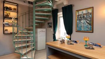 Una cocina compacta con una escalera en espiral, un refrigerador y un comedor con alimentos para el desayuno.