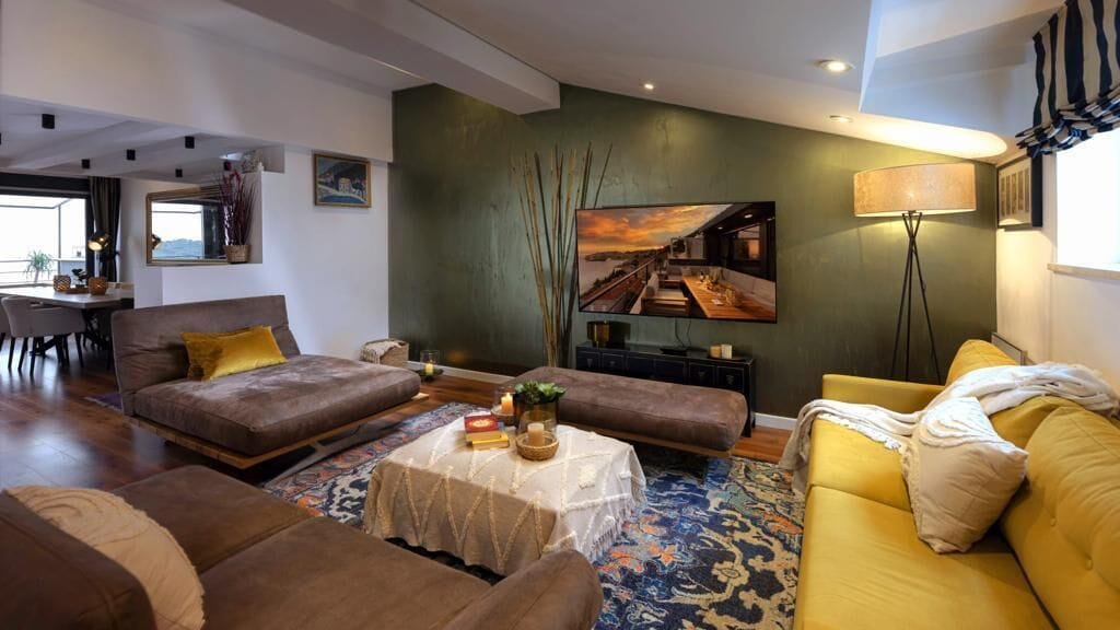 Ein modernes Wohnzimmer mit einer Couch, einem gelben Sessel, einem Couchtisch und einem Essbereich im Hintergrund.