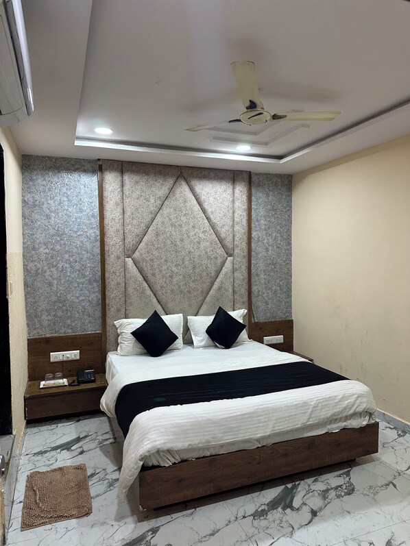 Une chambre à coucher bien rangée, avec un lit, des tables de chevet et un ventilateur de plafond.