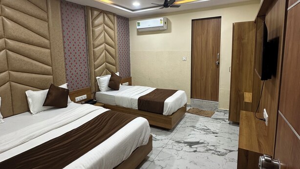 Une chambre d’hôtel avec deux lits, un ventilateur de plafond, un appareil de climatisation, une armoire en bois et un revêtement de sol en marbre.