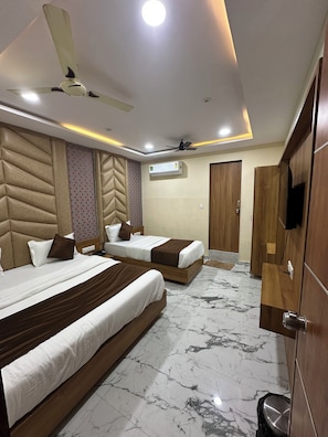 Une chambre d’hôtel avec deux lits, un ventilateur de plafond, un appareil de climatisation, une armoire en bois et un revêtement de sol en marbre.