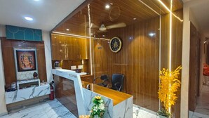 Un comptoir d’accueil avec un revêtement en marbre, des panneaux en bois, une horloge et un ventilateur de plafond.