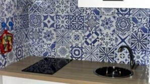 A kitchen with white cabinets, a black sink, and a patterned backsplash.