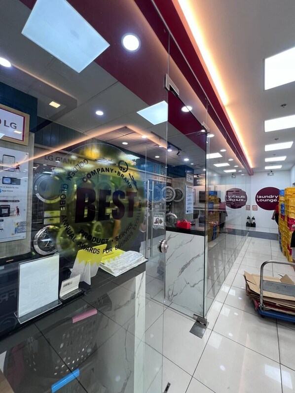A modern interior with a reception area, glass partitions, and a visible counter with promotional materials. - Unistay Coast Res R38 with Bal-Sunset Vw (Pasay)