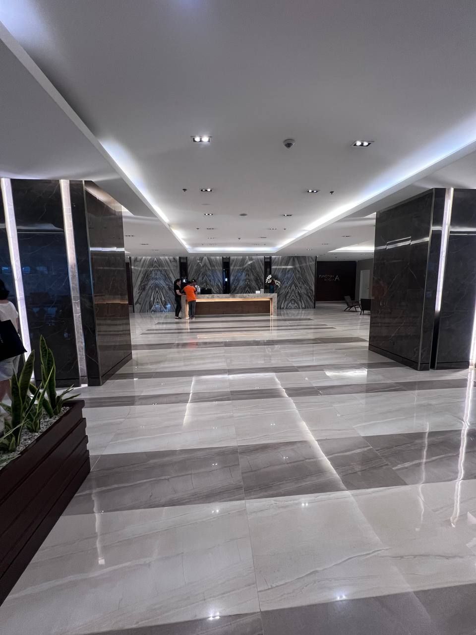 Eine geräumige Lobby mit einer Rezeption, Marmorböden und moderner Beleuchtung.