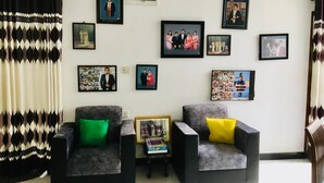 A living room with two armchairs, a coffee table, and a wall adorned with framed photographs. - Charming 1-bedroom house in beautiful Kandy with WiFi (Kandy)