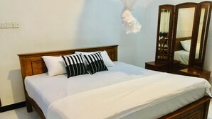 A neatly made bed with white bedding and striped pillows, a wooden headboard, and a bedside table with a mirror. - Charming 1-bedroom house in beautiful Kandy with WiFi (Kandy)