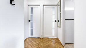 A room with two white doors, a wooden herringbone floor, and a black wall-mounted hook. - Lumina 2-room apart near Złote Tarasy (Warsaw)