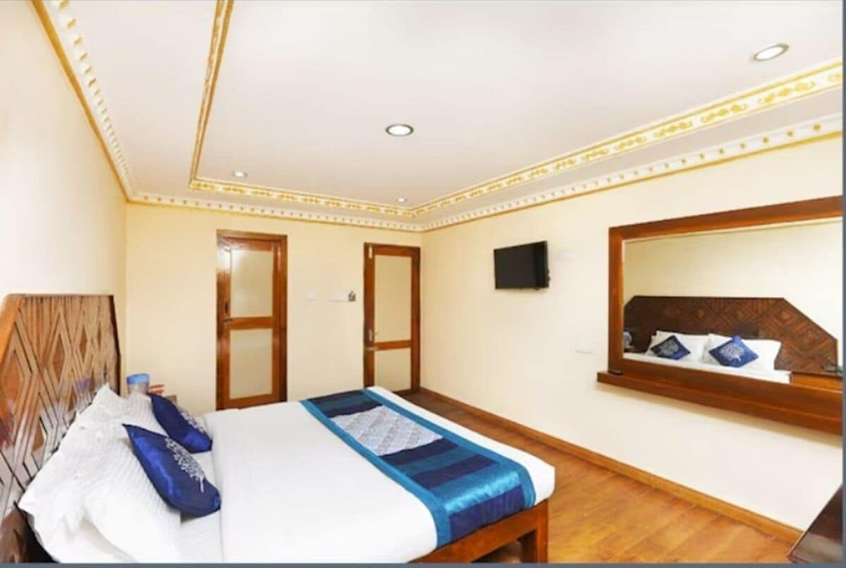 Una habitación de hotel con una cama, un espejo y un cabecero de madera.