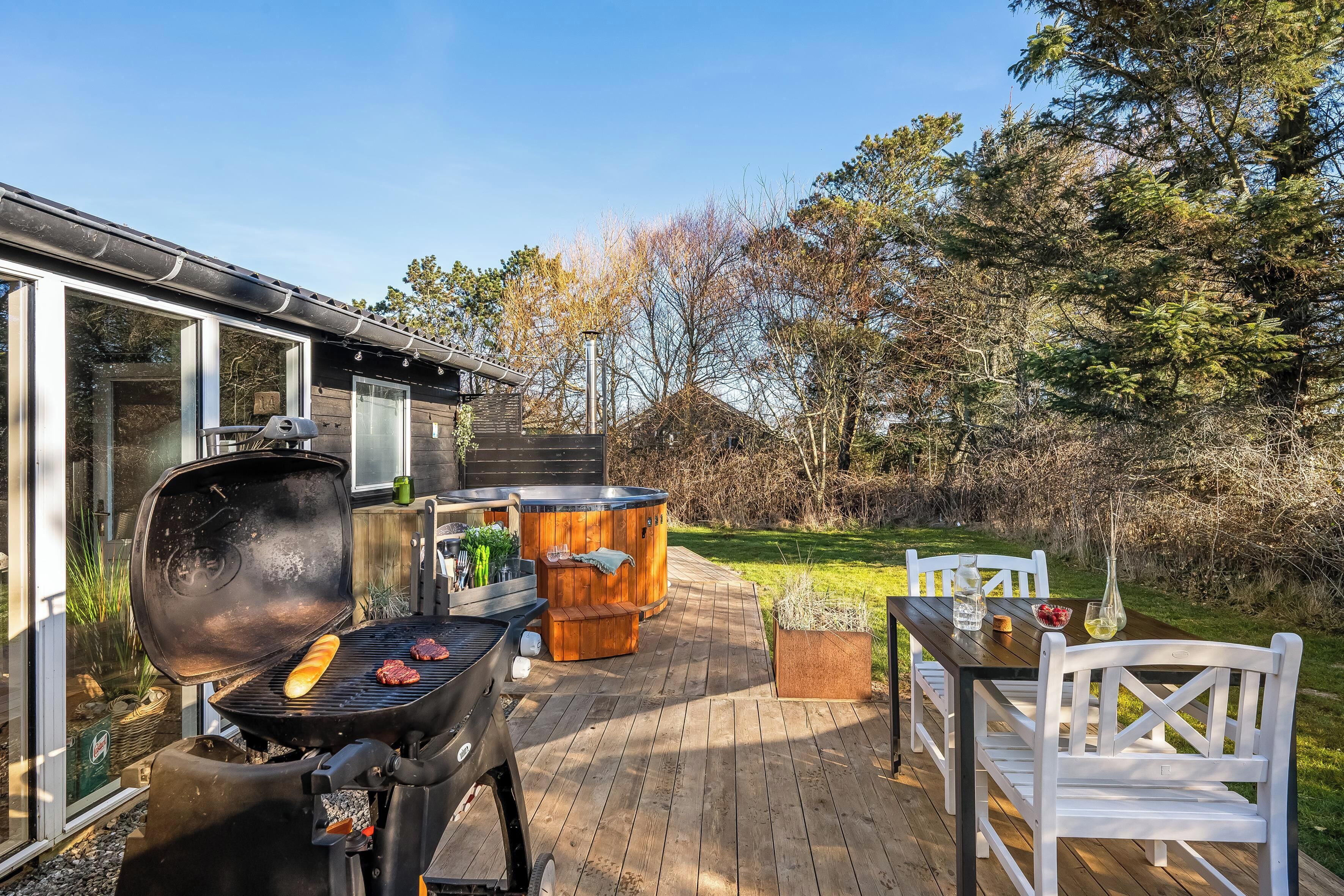 Eine Holzterrasse mit Grill, Whirlpool und Sitzbereich im Freien.