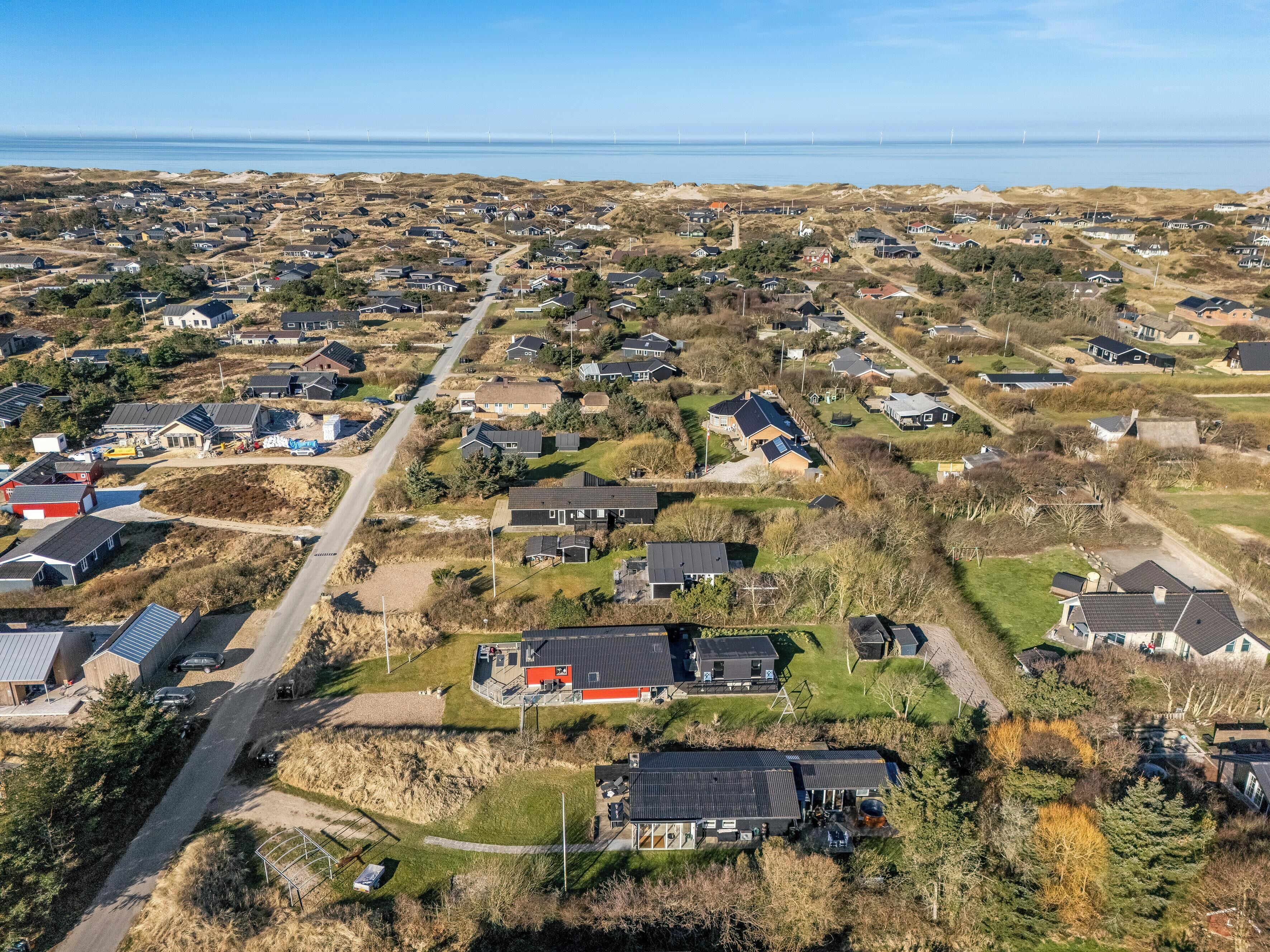 An aerial view of a residential area with houses, roads, and a body of water in the background.