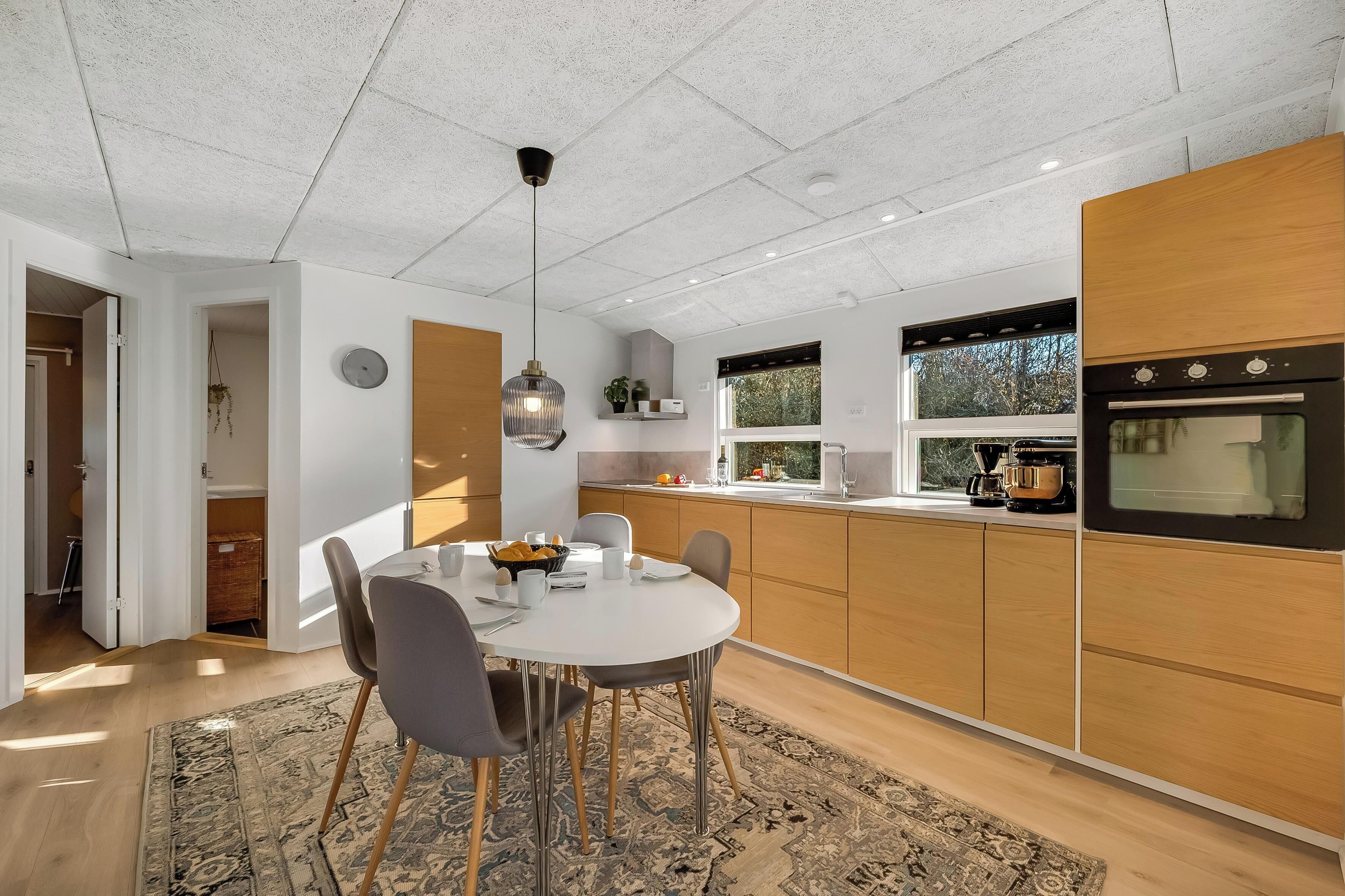Une cuisine moderne dotée d’un îlot central, de meubles en bois et d’un four encastré.