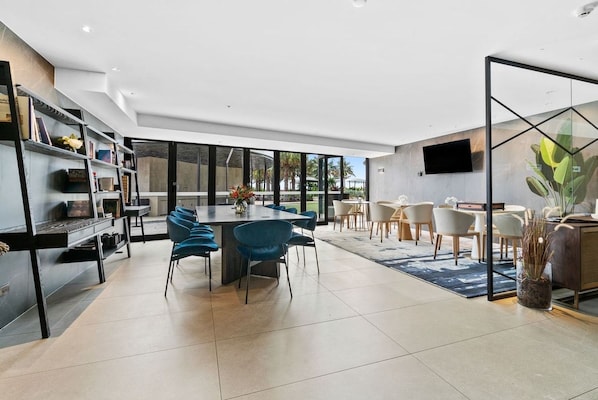A modern interior with a dining area, a bookshelf, and a TV mounted on the wall.