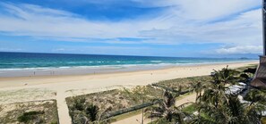 A beach with a clear sky, a sandy shore, and a view of the ocean.